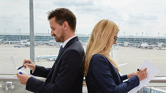 Ein Paar Rücken an Rücken vor einem Fenster mit Blick auf das Vorfeld Ein Paar Rücken an Rücken vor einem Fenster mit Blick auf das Vorfeld