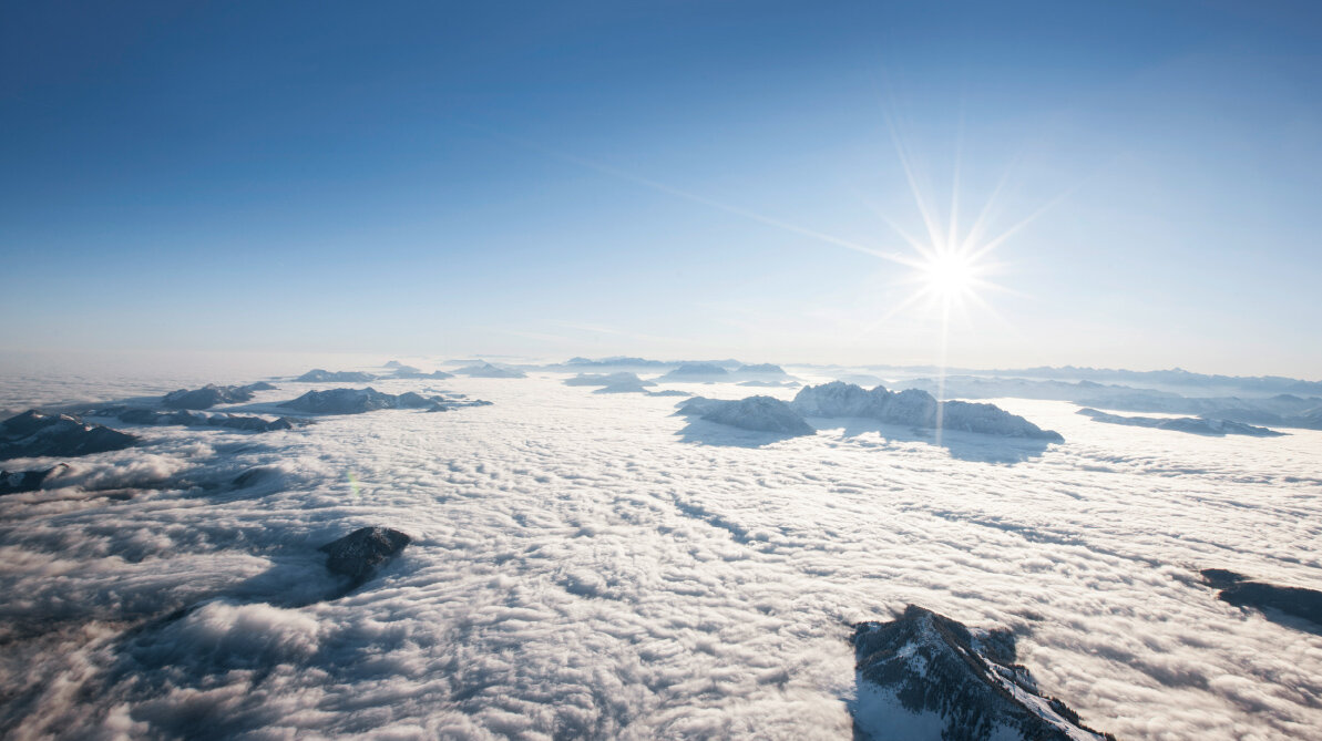 Eine geschlossene Wolkendecke über einem Gebirge, einige Berggipfel ragen heraus Eine geschlossene Wolkendecke über einem Gebirge, einige Berggipfel ragen heraus