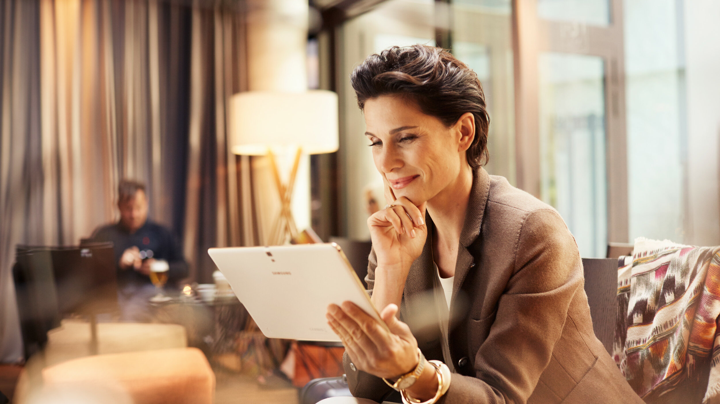 Sitzende Frau im Loungebereich mit einem Tablet-Computer in der Hand