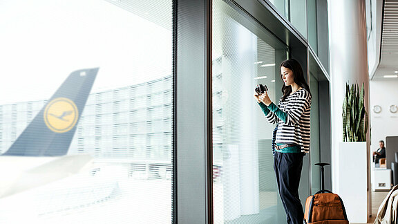 Eine Frau steht im Loungebereich und fotografiert das Vorfeld
