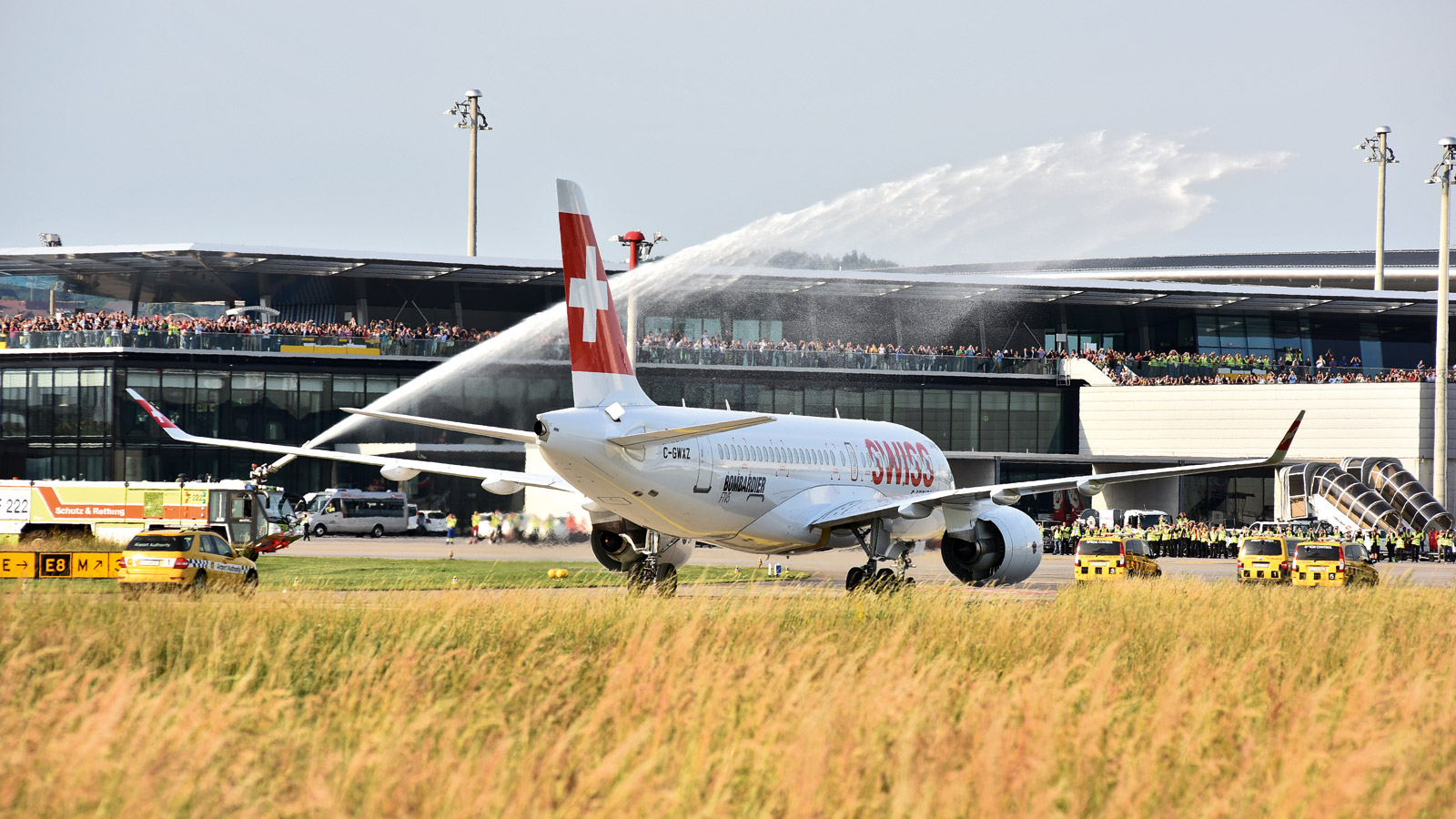 Eine Bombardier CS100 der SWISS auf der Rollbahn, begrüßt durch eine Fontaine eines Feuerlöschfahrzeugs